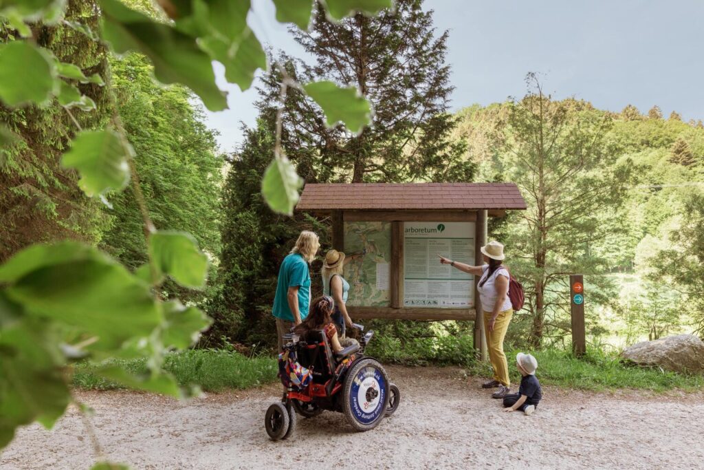 groupe devant un panneau de l'Arboretum, avec une personne en chaise roulante
