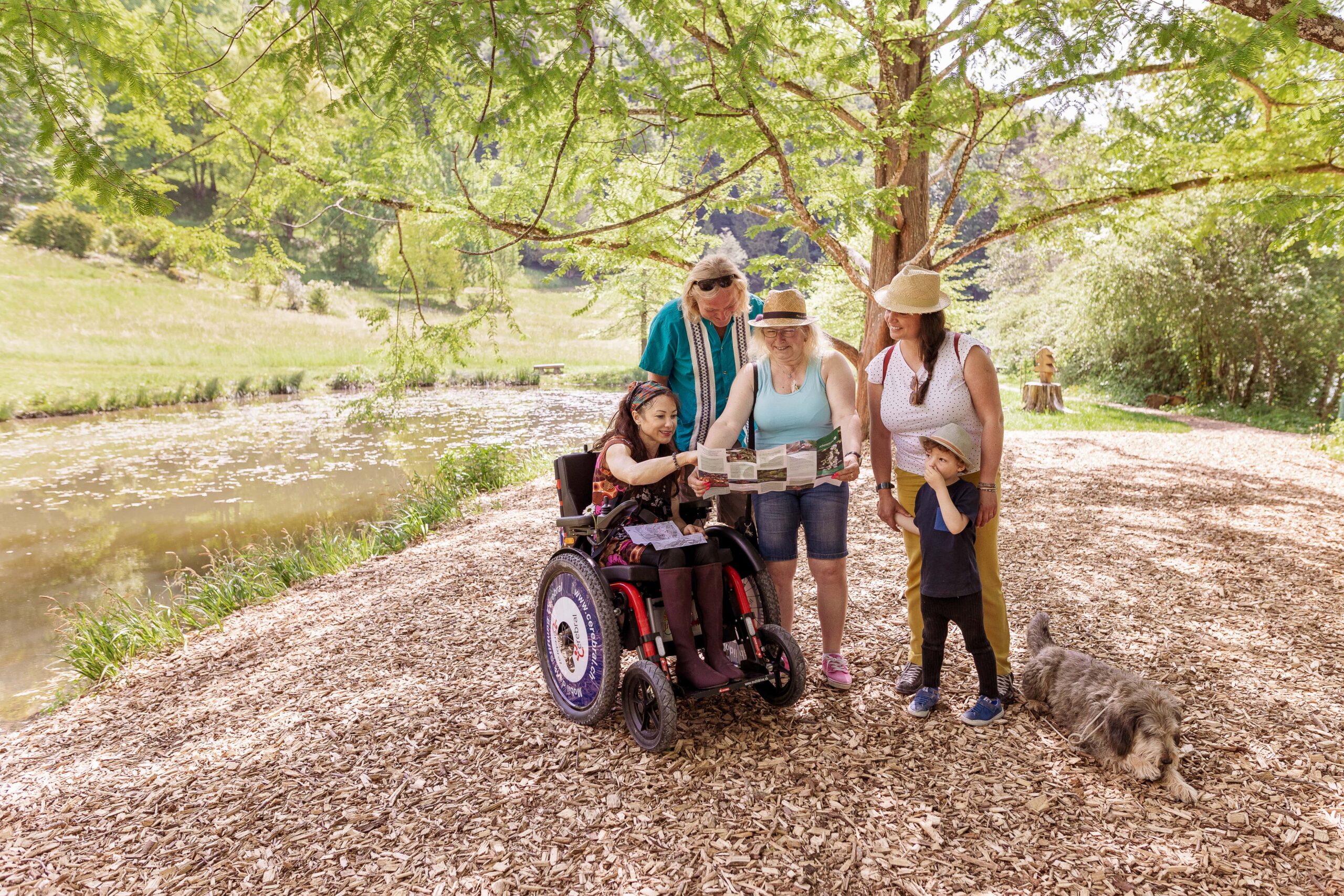 Groupe avec chaise roulante, au bord d'un lac, dans le parc