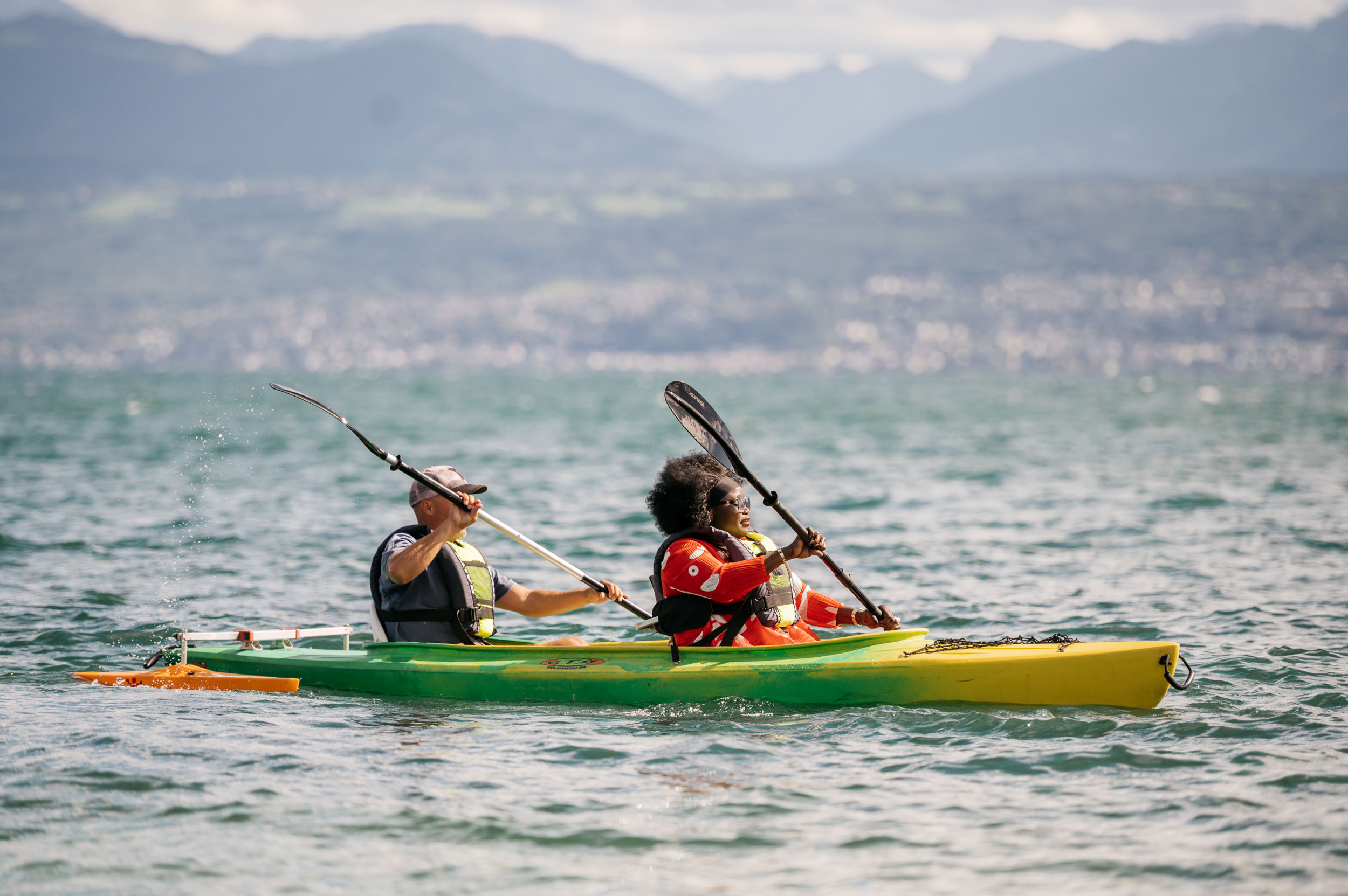 deux personnes sur un kayak, naviguent sur le Léman avec les montagnes dans le fond