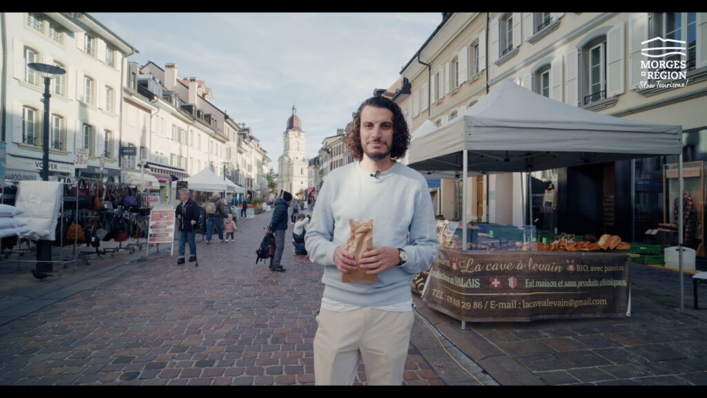 homme au marché de Morges avec le temple dans le fond 